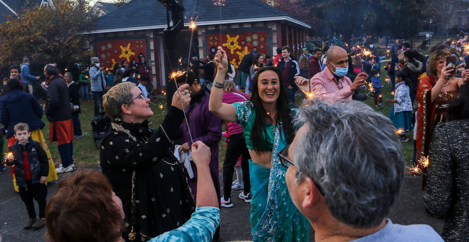 Lela Casey lights a sparkler, surrounded by others, at a festival