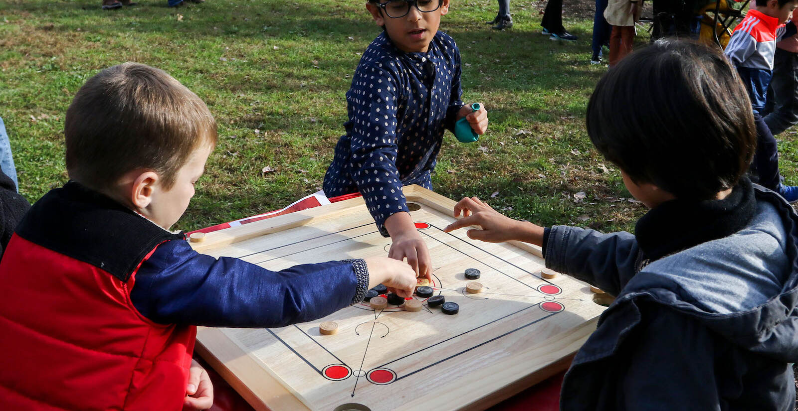 Jay Pasi, of Furlong, (center) teaching other kids how to play Carrom at the first annual Diwali festival in Doylestown on Nov. 7, 2021. (Daniella Heminghaus for WHYY)