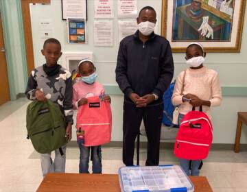 A father and his children pose for pictures after getting backpacks with school supplies at a visit with a local Delaware health care provider. (Courtesy of Jewish Family Services of Delaware)