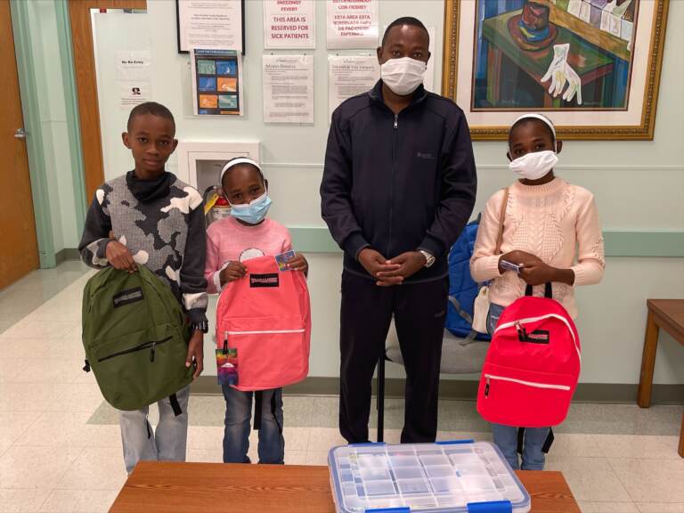A father and his children pose for pictures after getting backpacks with school supplies at a visit with a local Delaware health care provider. (Courtesy of Jewish Family Services of Delaware)
