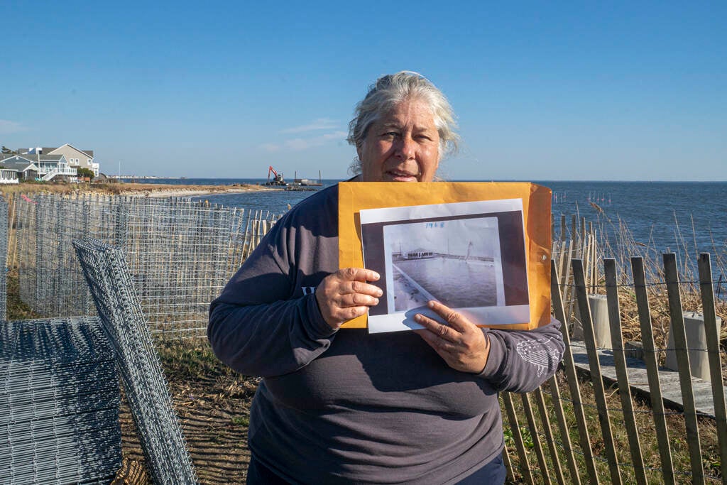 Pat Doyle holds up a black-and-white photograph of a large pool that was once a centerpiece of the Bayside Beach Club