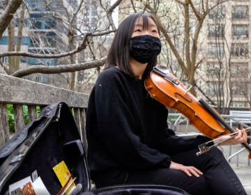 Grace Takeda wearing a mask playing her violin outside