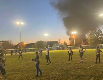 Young people play football at Lanier Park on Tuesday after a junkyard fire sent smoke into the air.