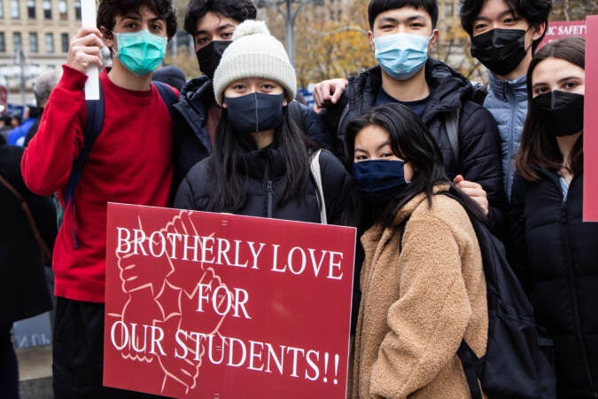 Alina Tran (front row, left) stands alongside others holding a protest sign that says, 