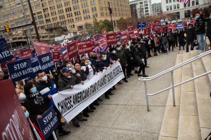 Protesters march toward the steps of a school district building with a sign that says, 