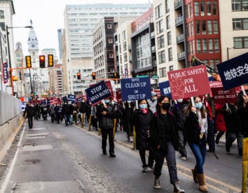 Protesters march down a Philadelphia street with signs that say, 