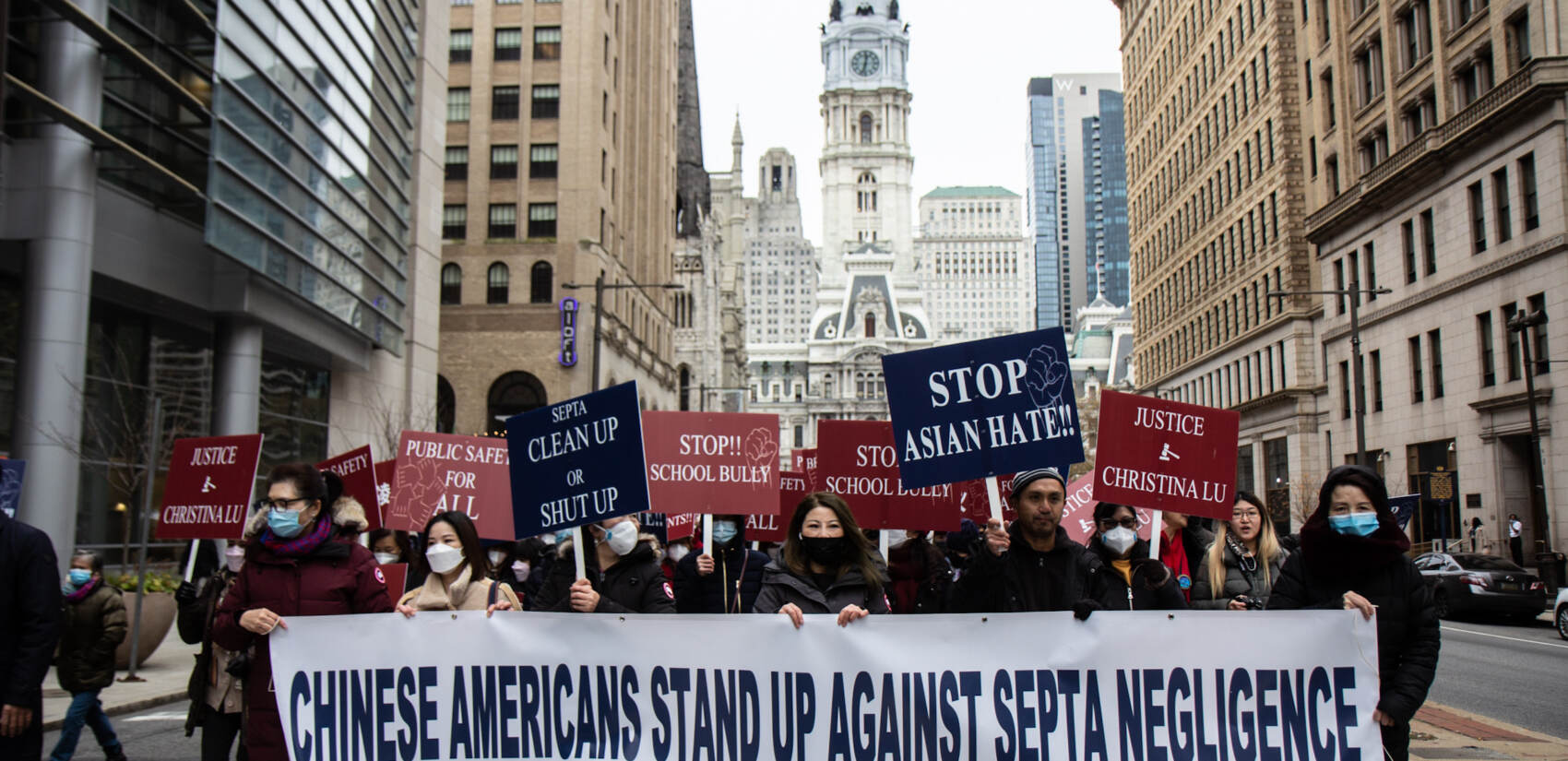 Protesters march away from City Hall with a sign that says, "Chinese Americans stand up against school negligence"