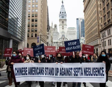 Protesters march away from City Hall with a sign that says, 