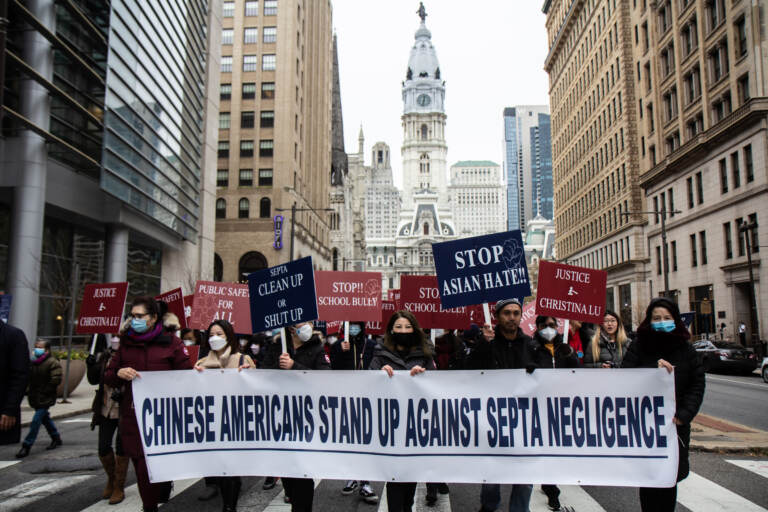 Protesters march away from City Hall with a sign that says, 