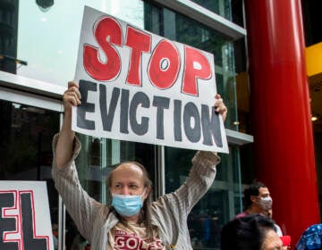 A housing advocate holds up a sign that says, 
