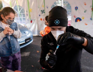 Leah Lefkove, 9, waits as her dad Dr. Ben Lefkove prepares the first COVID-19 vaccine for her at the Viral Solutions vaccination and testing site in Decatur, Ga., on the first day COVID-19 vaccinations were available for children from 5 to 12 on Wednesday, Nov. 3, 2021. The U.S. enters a new phase Wednesday in its COVID-19 vaccination campaign, with shots now available to millions of elementary-age children in what health officials hailed as a major breakthrough after more than 18 months of illness, hospitalizations, deaths and disrupted education. (AP Photo/Ben Gray)