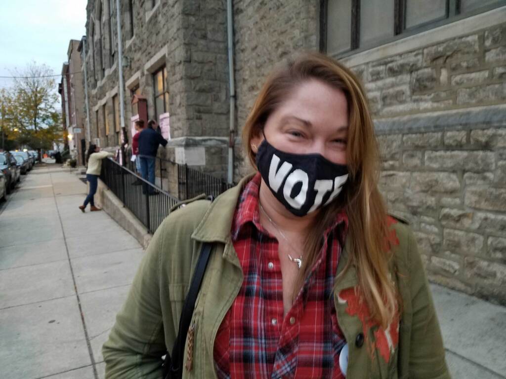 Jessica Spangler stands outside her polling place wearing a mask that says, "VOTE"