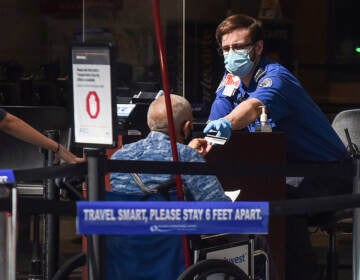 A man in a wheelchair hands his ID to a TSA officer