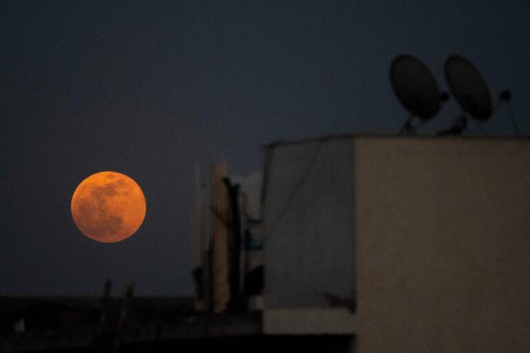 The super blood noon rises over a residential area in New Delhi during a total lunar eclipse in May. (Jewel Samad/AFP via Getty Images)