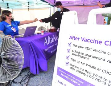 A nurse from AltaMed Health Services hands out a vaccine card