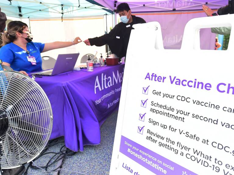 A nurse from AltaMed Health Services hands out a vaccine card