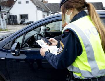 An Austrian police officer checks a driver's vaccination certificate