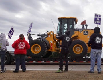 A truck hauls a piece of John Deere equipment