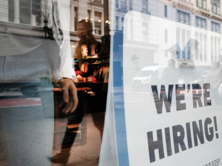 NEW YORK, NEW YORK - NOVEMBER 17: People walk by a hiring sign in a window along a main shopping street in Manhattan on November 17, 2021 in New York City. As Americans begin their holiday shopping early this year in an effort to avoid shortages of some goods, U.S. retail sales surged 1.7% last month, the largest gain since March