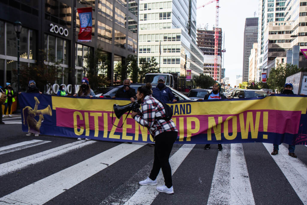 Protesters march in Philly, holding a sign that reads, "Citizenship Now!"