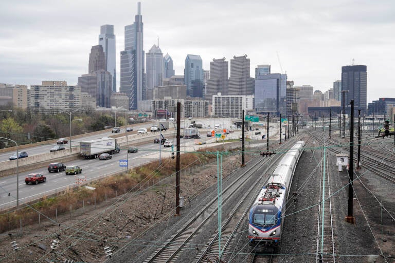 An Amtrak train departs 30th Street Station moving parallel to motor vehicle traffic on Interstate 76 in Philadelphia. (AP Photo/Matt Rourke)