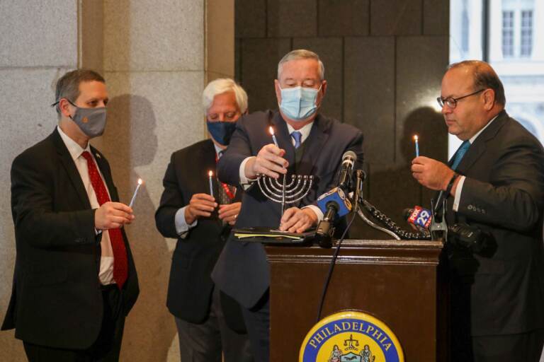 Philadelphia Mayor Jim Kenney (center), CEO of the Jewish Federation of Greater Philadelphia Michael Balaban, and Councilmember Allan Domb (right) light a Hanukkah menorah