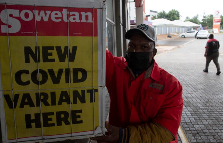 A petrol attendant uses next to a newspaper headline in Pretoria, South Africa, Saturday, Nov. 27, 2021. As the world grapples with the emergence of the new variant of COVID-19, scientists in South Africa — where omicron was first identified — are scrambling to combat its spread across the country. (AP Photo/Denis Farrell)