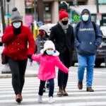 People wearing face masks walk through Philadelphia