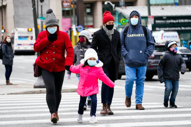 People wearing face masks walk through Philadelphia