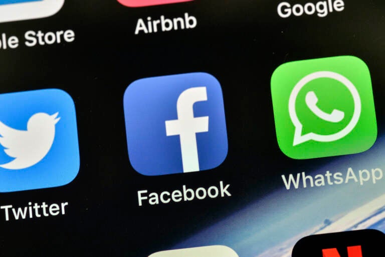 The icons of Facebook and WhatsApp are pictured on an iPhone