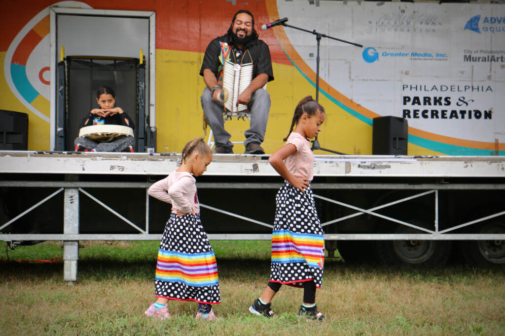 Kai'Lyn Ellis, 5, and her sister, Li'Ana Ellis, 10, members of the Nanticoke Lenape tribe, perform a toe dance while their father, Tyron Ellis chants at Philadelphia's Indigenous Peoples Day celebration at Penn Treaty Park