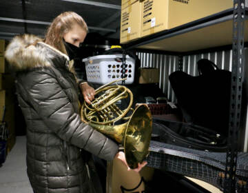 MaST Charter School music teacher Kelly Knittle evaluates a French horn as she selects instruments for her students from a trove of donated instruments offered by Musicopia