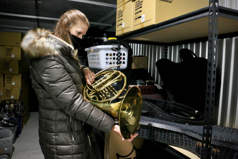 MaST Charter School music teacher Kelly Knittle evaluates a French horn as she selects instruments for her students from a trove of donated instruments offered by Musicopia