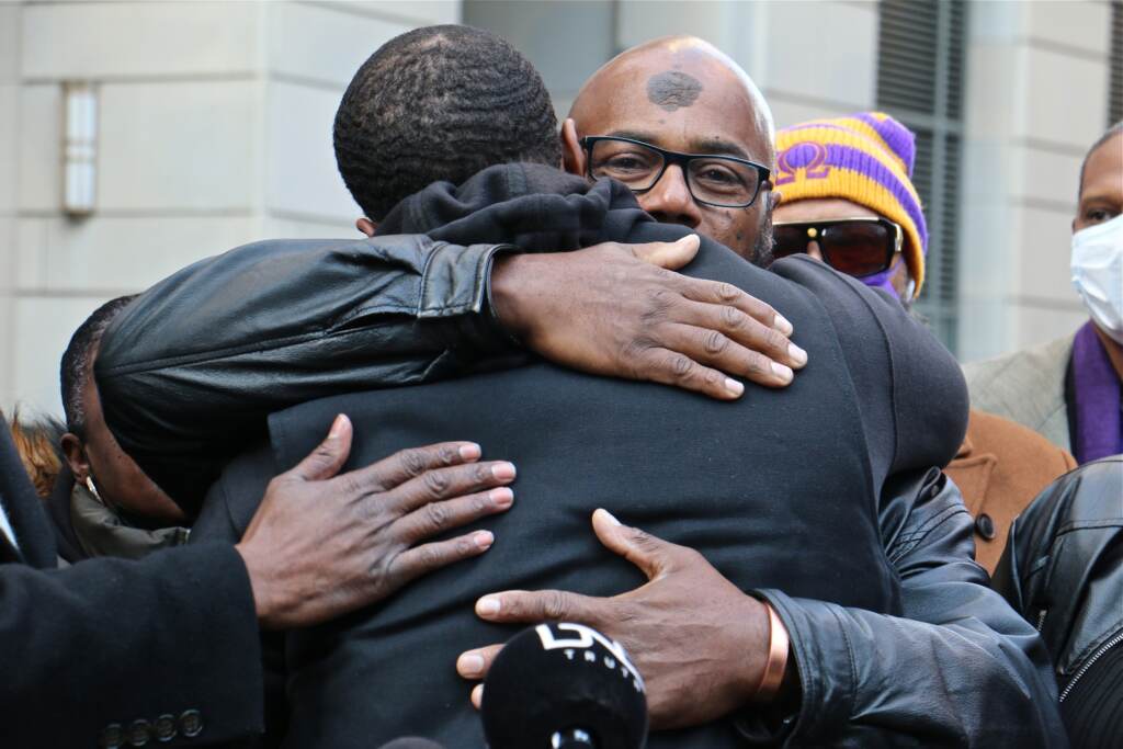 Chris Williams embraces his son, Chris Hartwell, during a press conference