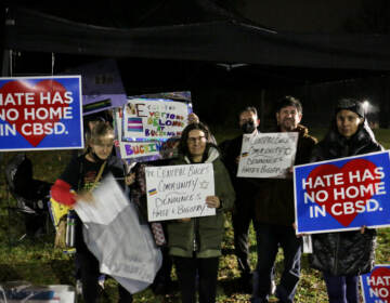 Demonstrators hold sign sin support of LGBTQ people outside a school board meeting