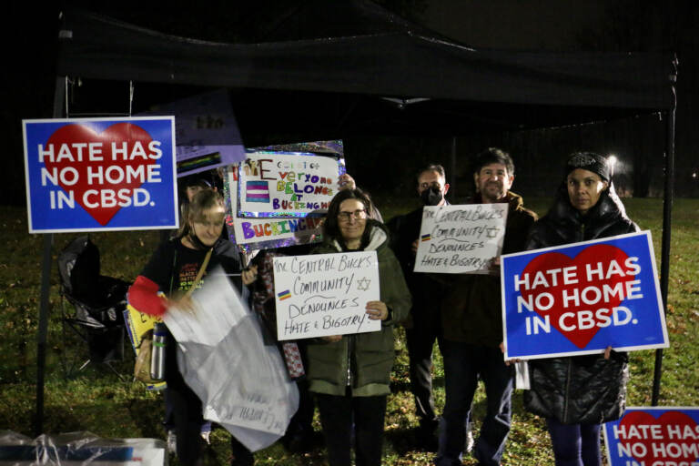 Demonstrators hold sign sin support of LGBTQ people outside a school board meeting