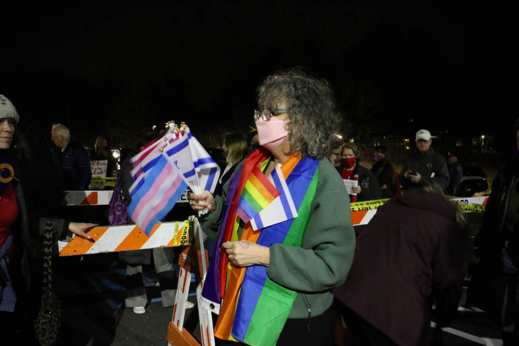 Roberta Gluck hands out flags to people waiting in line