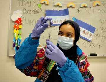 Dr. Hajar Mokhlis, a pharmacist with the Jefferson COVID-19 mobile unit, prepares vaccine doses in the art room at Universal Institute Charter School in South Philadelphia