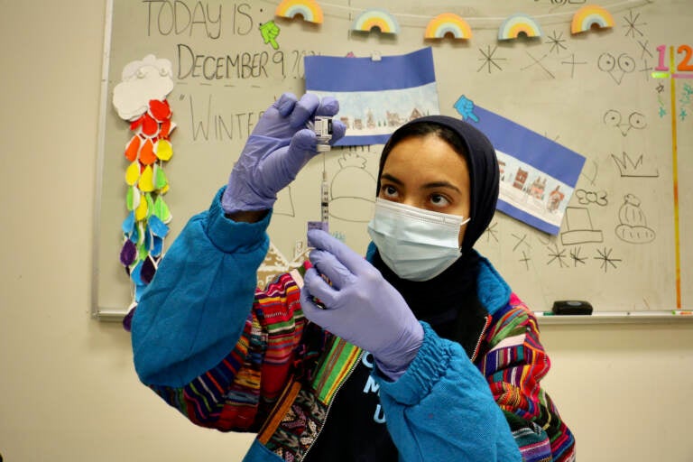 Dr. Hajar Mokhlis, a pharmacist with the Jefferson COVID-19 mobile unit, prepares vaccine doses in the art room at Universal Institute Charter School in South Philadelphia