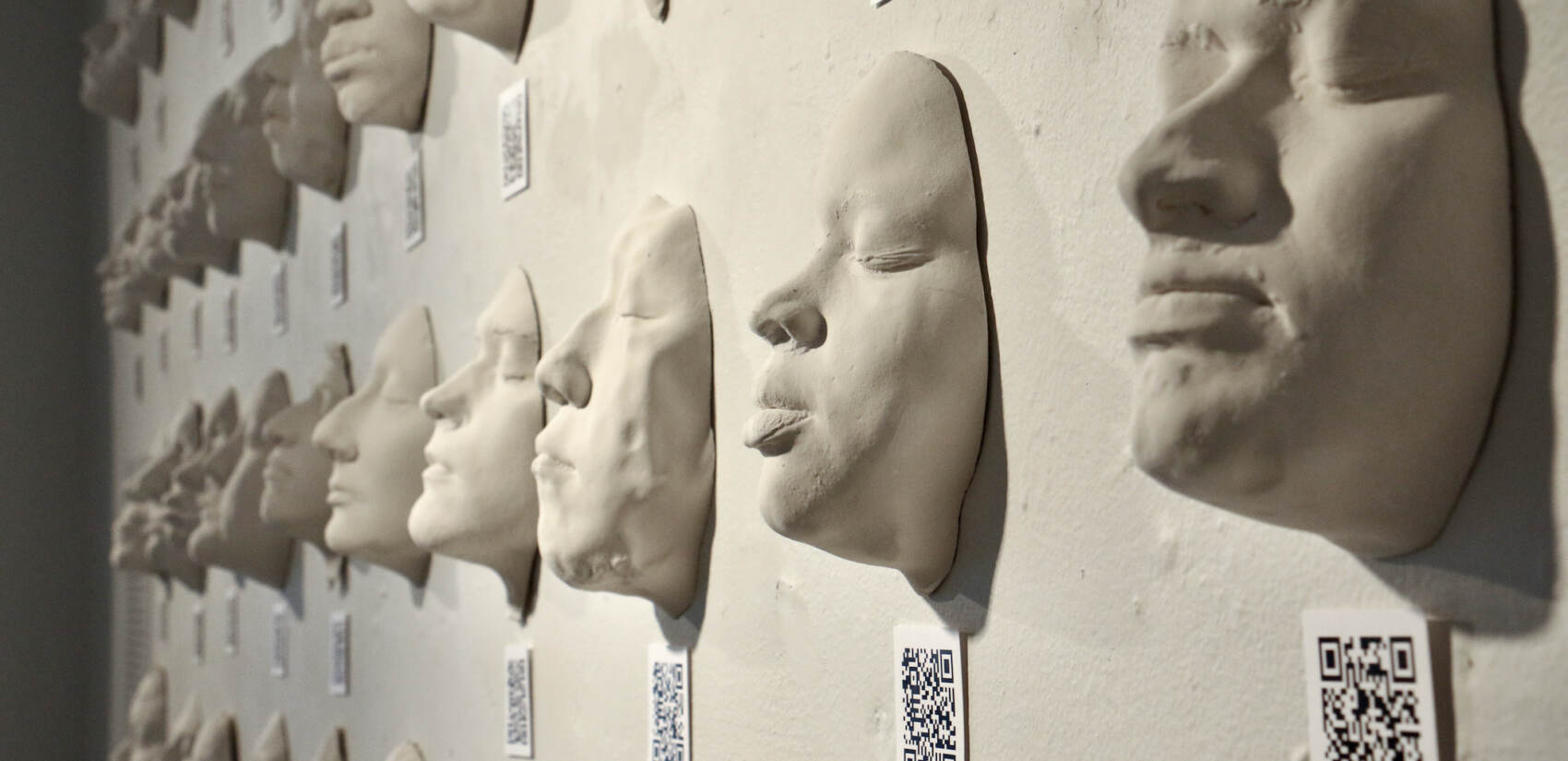 Dozens of students enrolled in University of Pennsylvania's introductory anthropology course made plaster casts of their own faces. In the exhibit, each is accompanied by a QR code that leads viewers to discover details about the individual. (Emma Lee/WHYY)