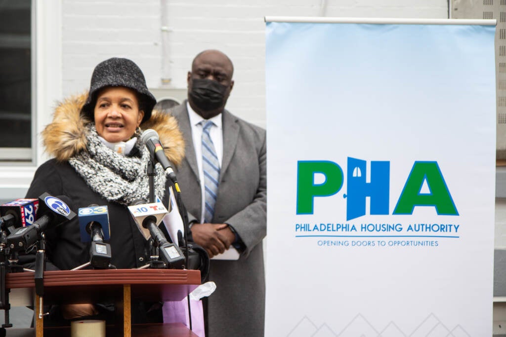 Ruth Birchett speaks from a podium next to PHA signage