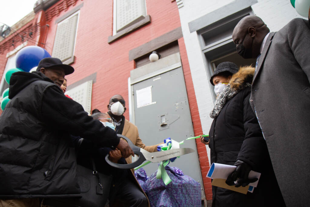 Officials and new residents help cut the ribbon on a rehabbed PHA home