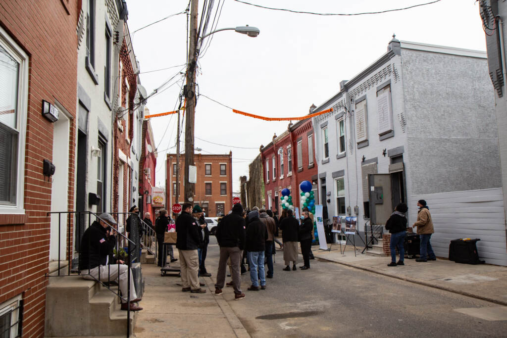 Officials and new residents stand outside rowhouses in Philly