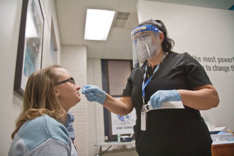 Jill Farina, an Olney Charter High School history teacher, said she was supportive of virtual learning over the holidays for the safety of students, teachers and their families, as she got tested for COVID-19 by Luz Costano, COVID Coordinator, on December 23, 2021. (Kimberly Paynter/WHYY)