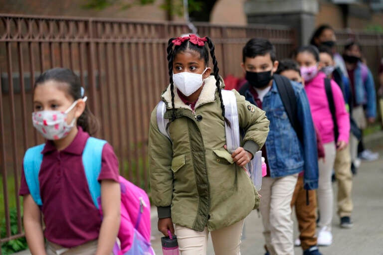 In this April 29, 2021, file photo, students line up to enter Christa McAuliffe School in Jersey City, N.J. Children are having their noses swabbed or saliva sampled at school to test for the coronavirus. As more children return to school buildings this spring, widely varying approaches have emerged on how and whether to test students and staff members for the virus.