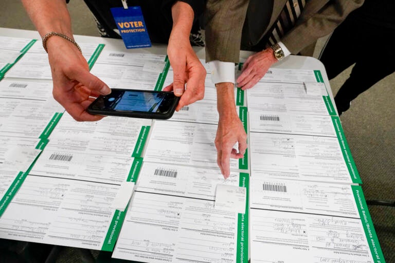 A canvas observer photographs Lehigh County provisional ballots as vote counting in the general election continues, Nov. 6, 2020, in Allentown, Pa. A review by The Associated Press in the six battleground states disputed by former President Trump has found fewer than 475 cases of potential voter fraud, a minuscule number that would have made no difference in the 2020 presidential election. (AP Photo/Mary Altaffer, file)