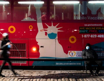 A mobile COVID-19 vaccination and booster shot site operates out of a bus on 59th Street south of Central Park as patients wait on the sidewalk, Thursday, Dec. 2, 2021, in New York. Health officials say multiple cases of the omicron coronavirus variant have been detected in New York, including a man who attended an anime convention in Manhattan in late November and tested positive for the variant when he returned home to Minnesota. (AP Photo/John Minchillo)