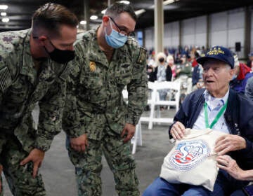 Pearl Harbor survivor and World War II Navy veteran David Russell, 101, of Albany, NY, shows off his commemorative bag to two military personnel before the start of the 80th Pearl Harbor Anniversary ceremony at Joint Base Pearl Harbor-Hickam, Tuesday, Dec. 7th, 2021, in Honolulu