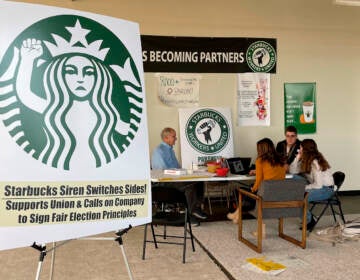 FILE- Richard Bensinger, left, who is advising unionization efforts, along with baristas Casey Moore, right, Brian Murray, second from left, and Jaz Brisack, second from right, discuss their efforts to unionize three Buffalo-area stores, inside the movements headquarters on Oct. 28, 2021 in Buffalo, N.Y. The National Labor Relations Board is scheduled to count ballots Thursday, Dec. 9, 2021, from union elections held at three separate Starbucks stores in the Buffalo area. Around 111 Starbucks workers from the three stores were eligible to vote by mail starting last month.(AP Photo/Carolyn Thompson, File)