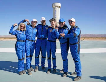 Blue Origin's latest space passengers from left, Laura Shepard Churchley, Dylan Taylor, Michael Strahan, Cameron Bess, Lane Bess, and Evan Dick pose for a photo in front of the booster rocket at the spaceport near Van Horn, Texas, Saturday, Dec. 11, 2021